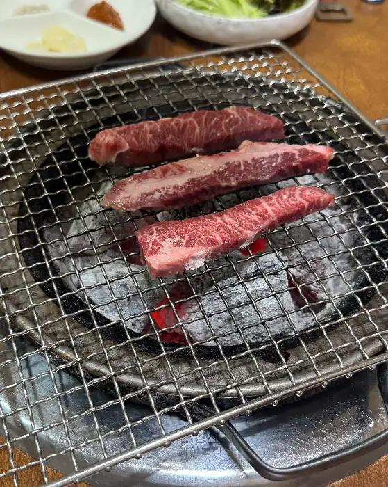 숯불 위에서 구워지는 세 덩이의 소고기