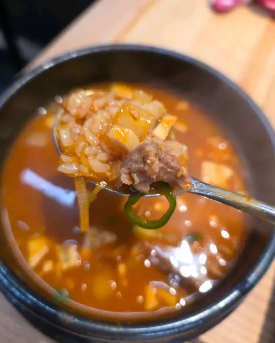 숟가락으로 떠낸 된장찌개의 모습. 두부, 고기, 밥알 등이 보인다.