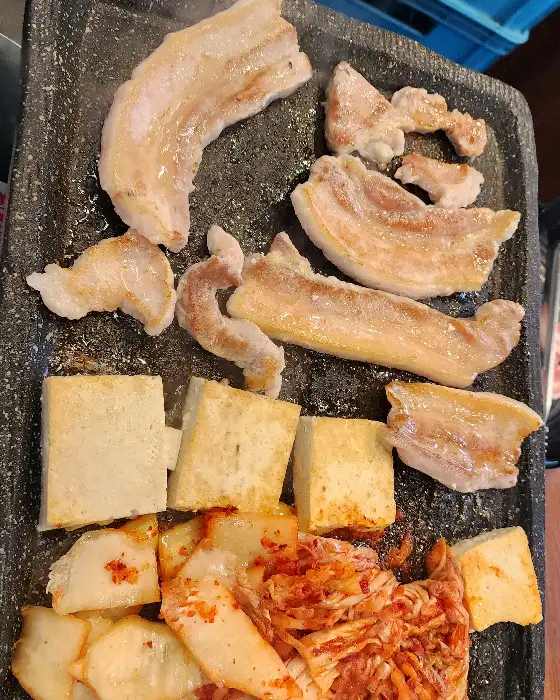 불판 위 삼겹살과 두부, 김치