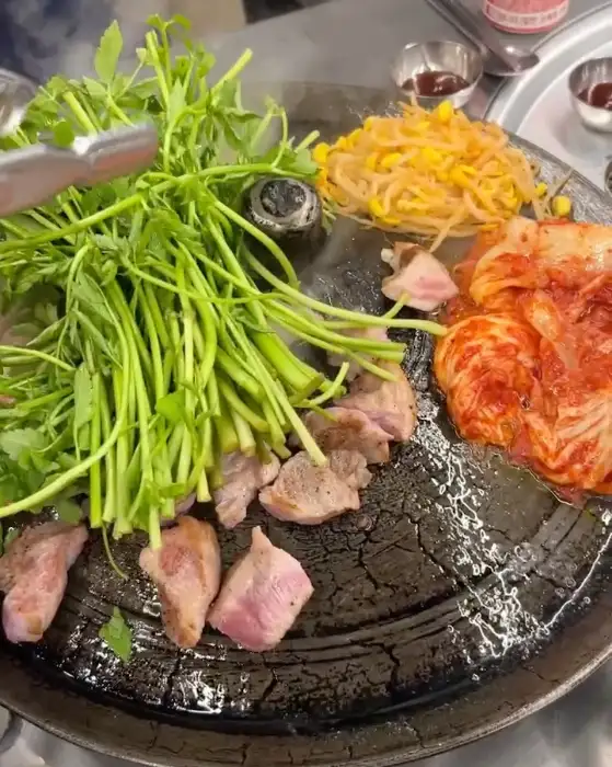 미나리와 함께 솥뚜껑에서 구워지는 삼겹살