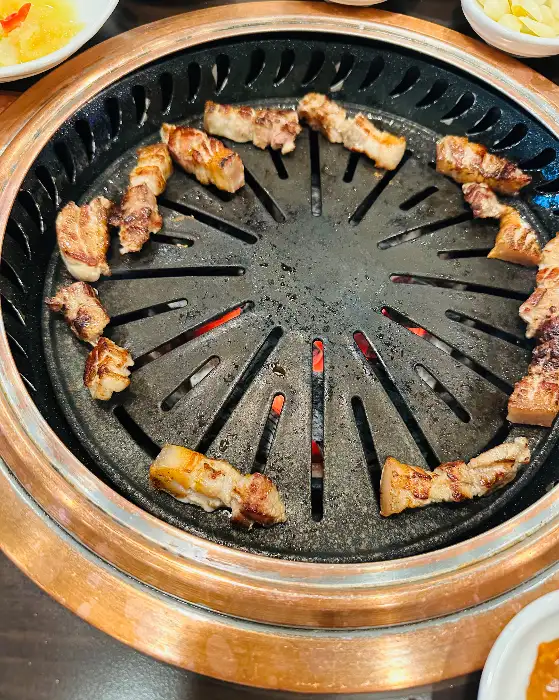 숯불 위에서 노릇하게 구워지는 삼겹살 조각들