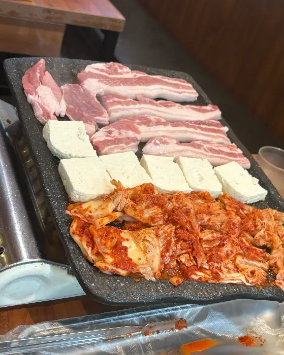불판 위에 올라간 삼겹살, 두부, 김치