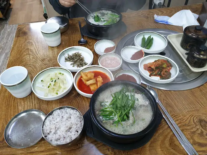 앞서 본 이미지와 유사한 상차림. 뚝배기 안의 국밥과 밥, 그리고 다양한 반찬들이 보인다.