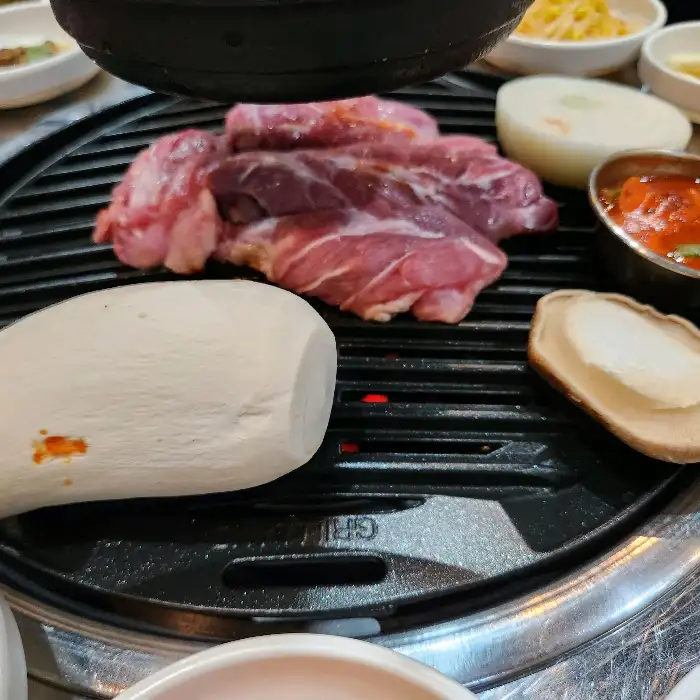 숯불 위에서 익어가는 갈매기살과 버섯