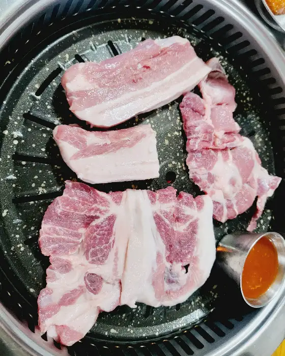 숯불 그릴 위에서 익고 있는 두툼한 삼겹살 덩어리