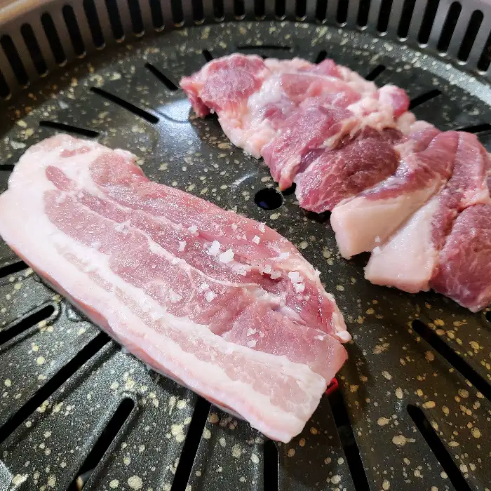 숯불 그릴 위 두 덩어리의 돼지고기