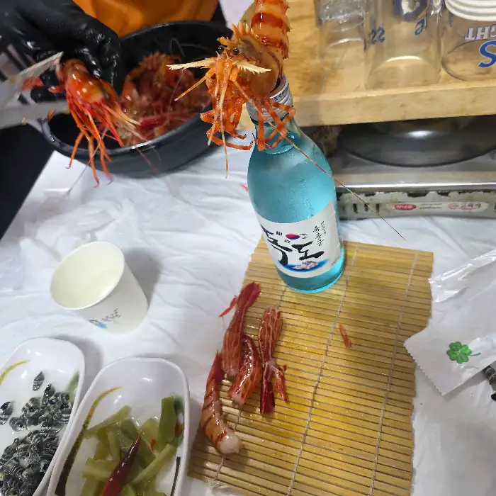 독도새우를 집는 손과 술병
