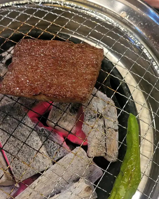 숯불 위에서 맛있게 구워지고 있는 소고기 한 점