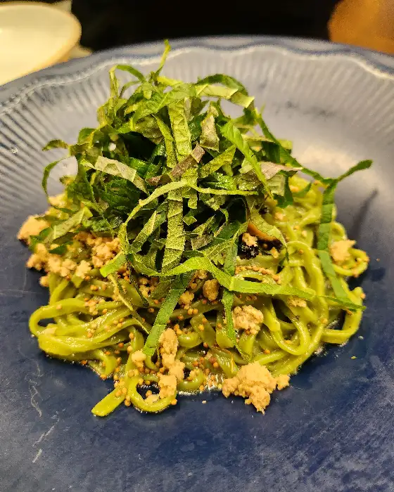 담백한 맛의 들기름 칼국수, 초록색 면과 다진 고명이 올라가 있음