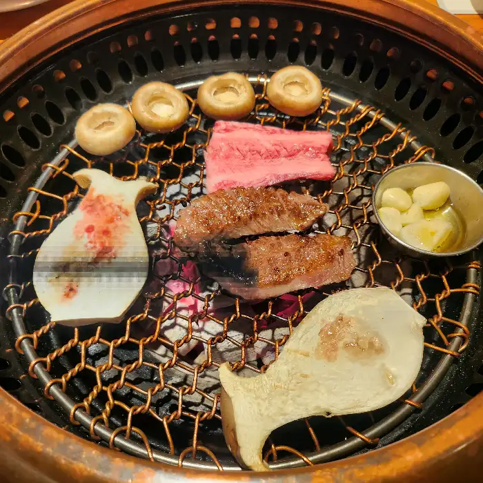 불판 위에 구워지고 있는 소고기와 버섯, 마늘