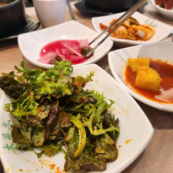 여러 반찬과 깍두기, 김치가 담긴 접시들