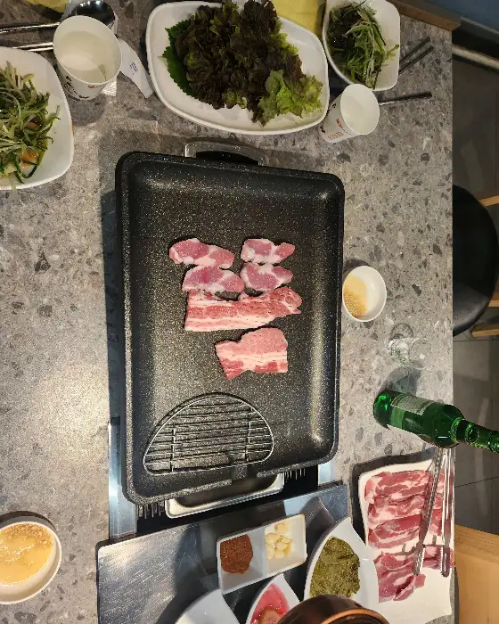 다양한 곁들임 반찬과 함께 불판에 구워지는 고기