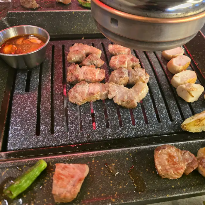 숯불 위에서 구워지는 삼겹살과 곁들임 재료