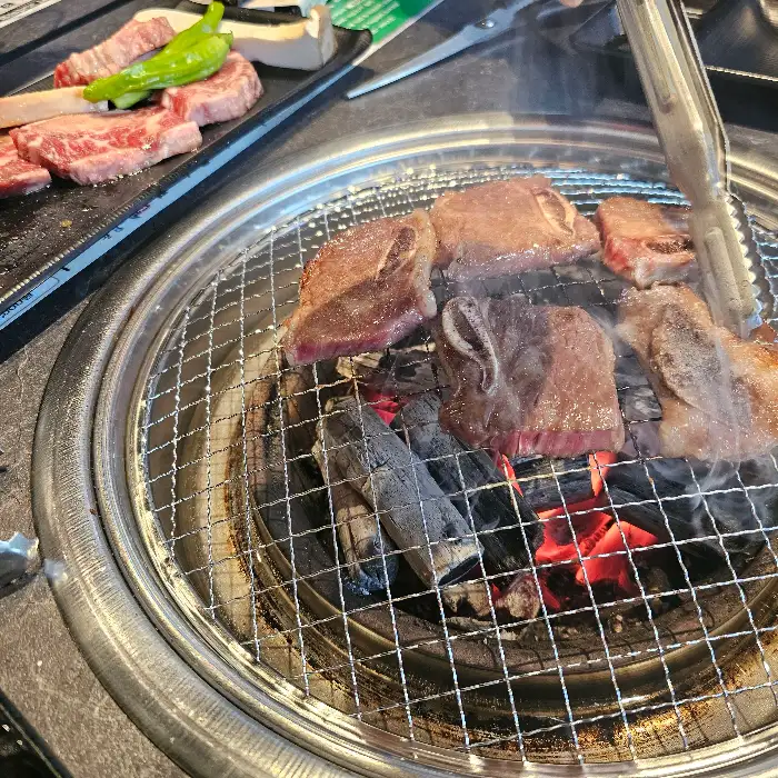 집게로 집어 올린 윤기 나는 돼지갈비
