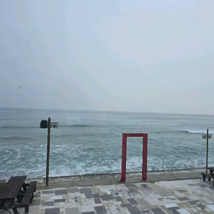 카페 외부 테라스에 설치된 붉은색 프레임 포토존과 바다 풍경