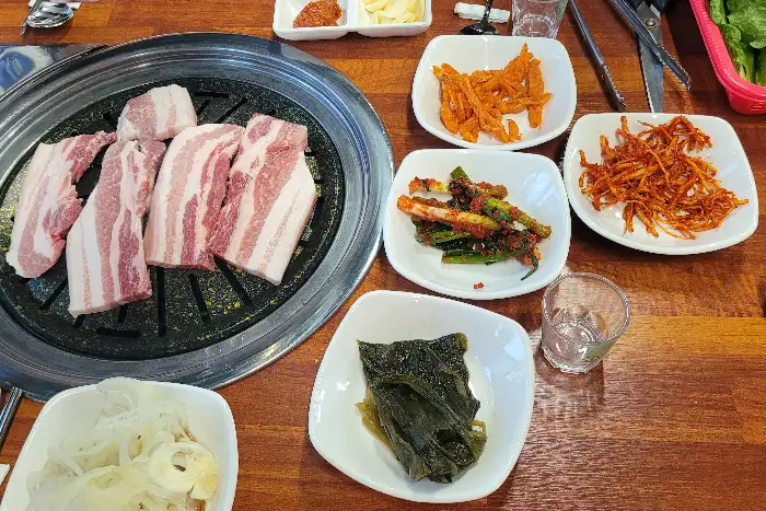 불판 위에서 구워지는 삼겹살과 반찬들