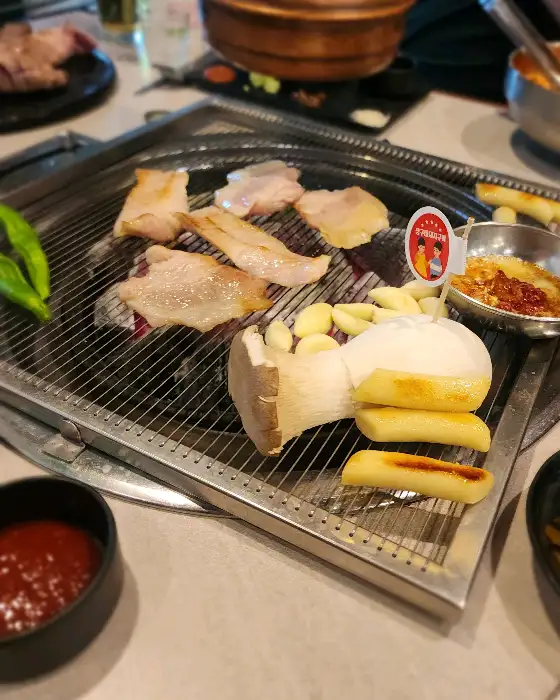 불판 위에서 다양하게 구워지는 고기와 곁들임 재료들