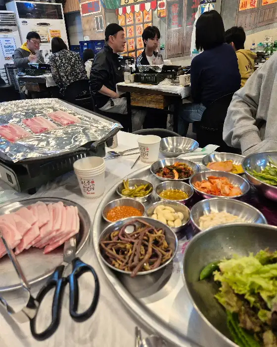 테이블 가득 차려진 냉동 삼겹살과 다양한 밑반찬