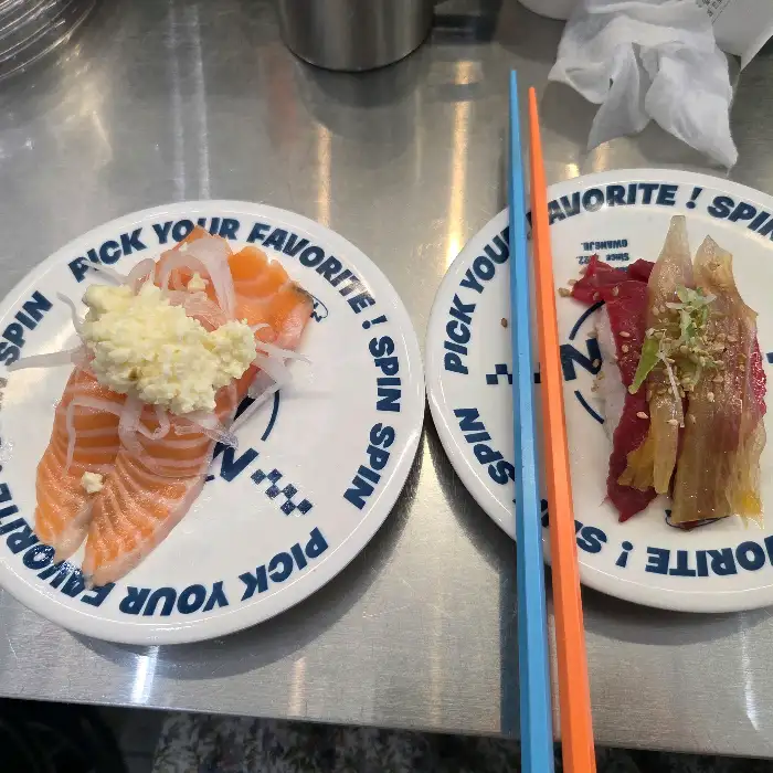 접시에 담긴 연어 초밥과 소고기 초밥, 그리고 젓가락이 놓여 있다.