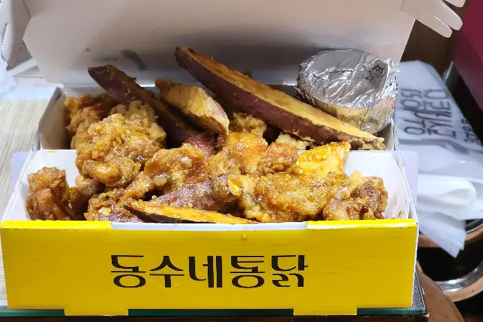 노란색 치킨 박스에 담긴 치킨과 고구마 튀김