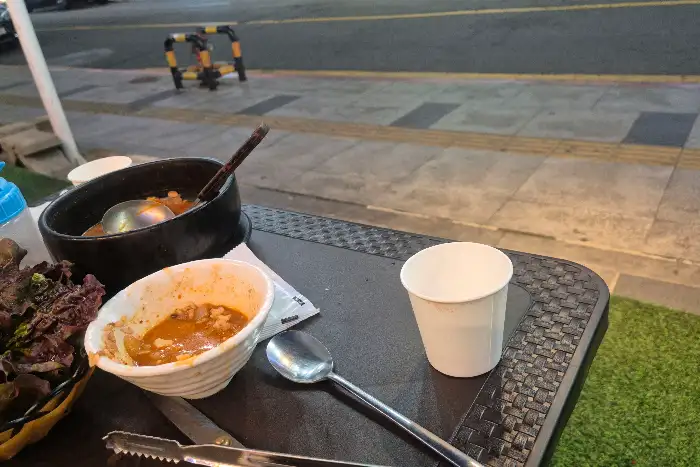 테이블 위에 놓인 찌개와 샐러드, 그리고 컵