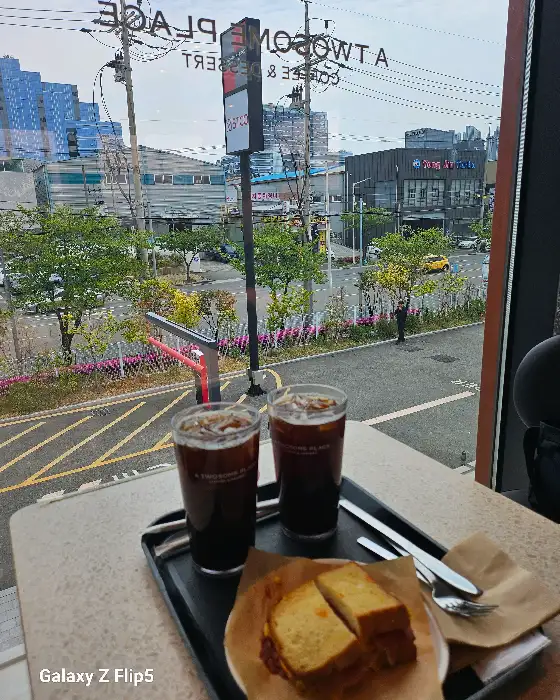 테이블 위에 놓인 두 잔의 아이스 아메리카노와 샌드위치