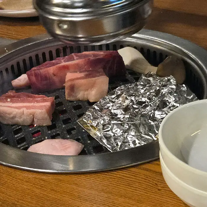 숯불 위에서 맛있게 익어가는 삼겹살과 버섯