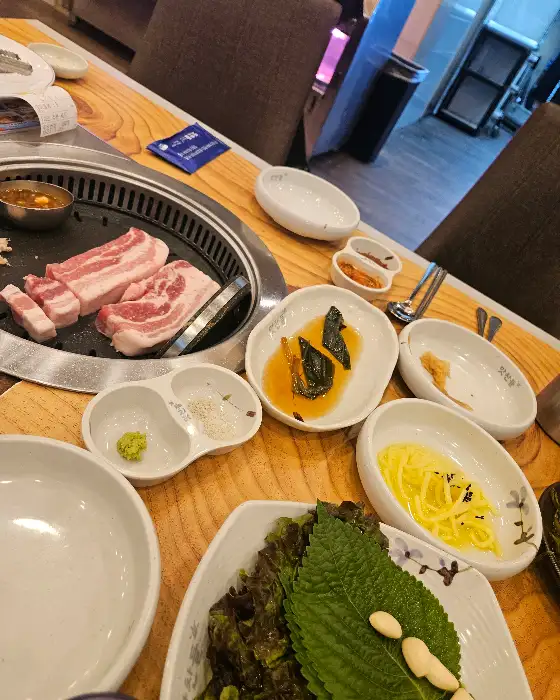 다양한 곁들임 찬과 삼겹살이 테이블 위에 차려져 있다.