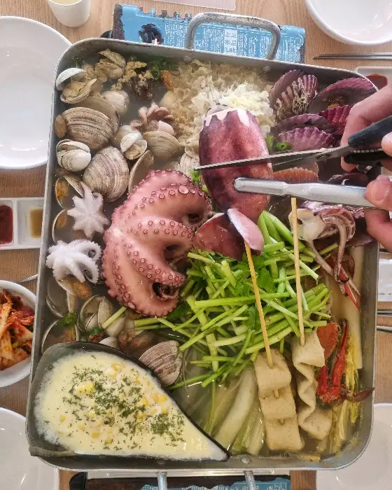 해물 조개찜을 집게로 집고 있는 모습
