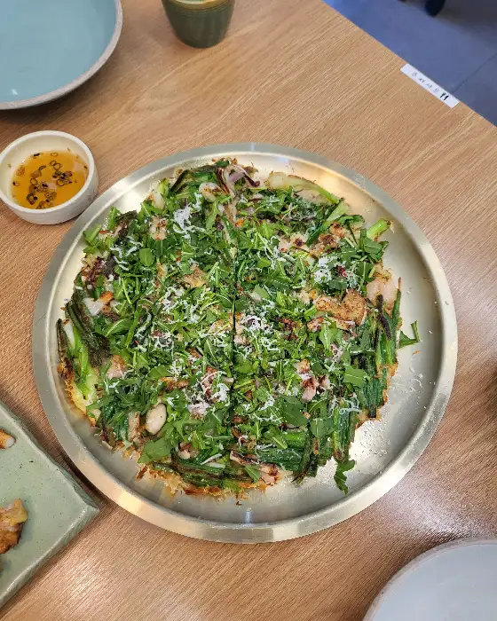 푸짐한 해물파전, 녹색 채소와 각종 해산물이 듬뿍 올라가 있어 먹음직스러움