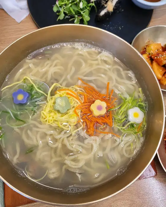 신사와 칼국수의 물총 칼국수 비주얼, 꽃 모양의 고명이 올라가 있고 면이 쫄깃해 보임