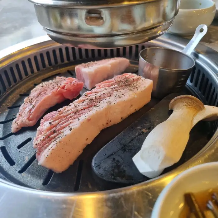 두툼한 꽃목살과 삼겹살 덩어리가 불판에 올라갈 준비를 하고 있는 모습