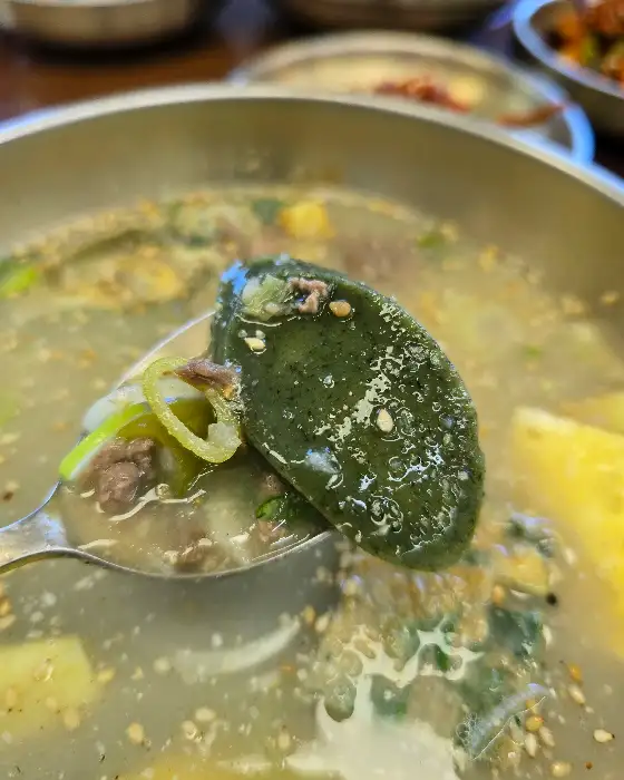 숟가락으로 떠낸 깻잎 떡국 내용물