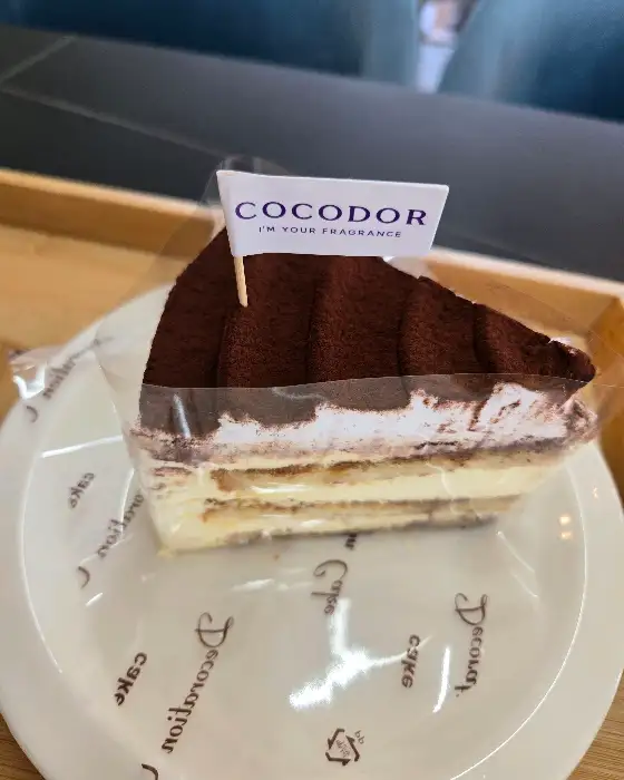 COCODOR 로고가 새겨진 깃발이 꽂힌 티라미수 케이크.