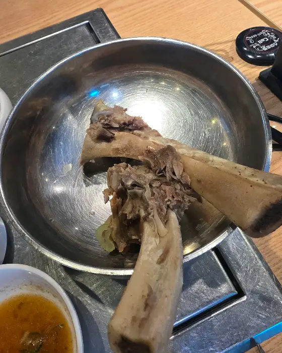 불판 위에 놓인 큼직한 갈빗대와 곁들임 소스