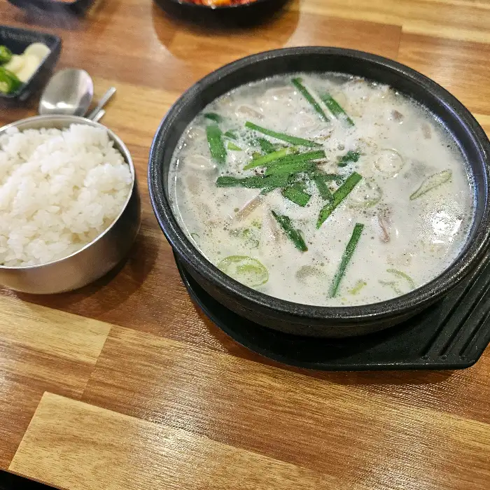 그릇 가득 담긴 뽀얀 국물의 돼지국밥과 밥