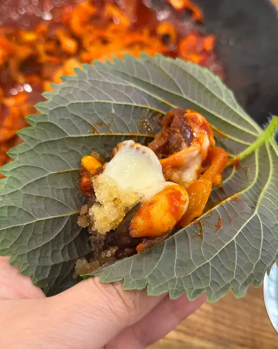 깻잎에 쭈꾸미와 치즈를 싸 먹는 모습