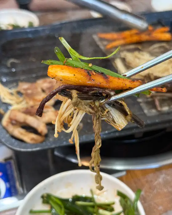 그릴 위에서 지글지글 구워지는 흑돼지 삼겹살, 더덕구이, 팽이버섯, 마늘