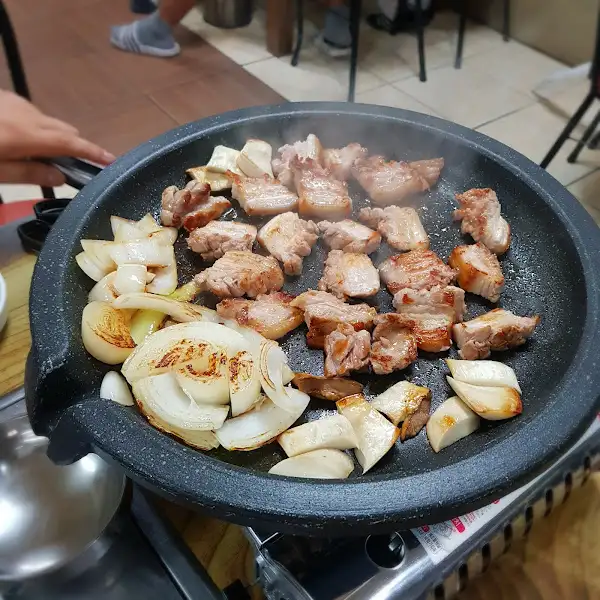 불판 위에서 익고 있는 삼겹살, 양파, 버섯
