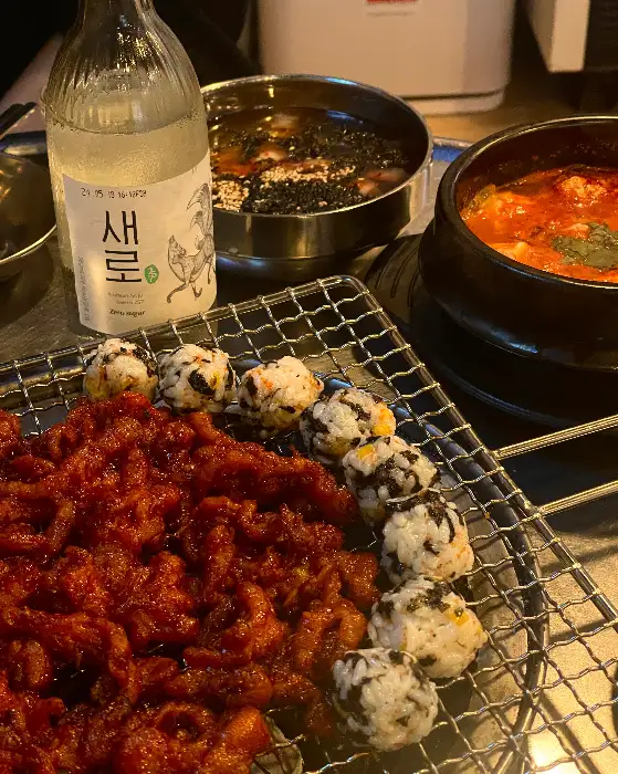 닭발과 날치알 주먹밥, 술이 함께 놓여진 테이블