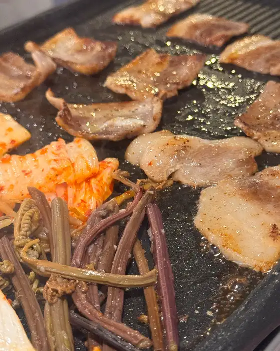 불판 위에서 익어가는 냉삼과 반찬들