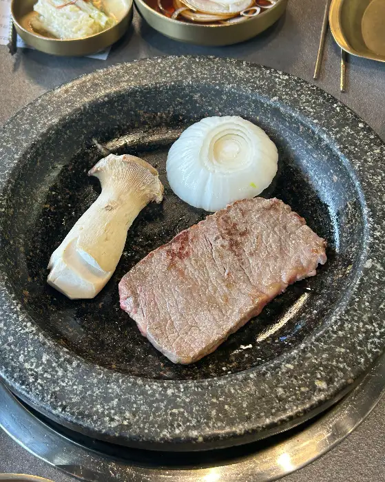 팬에 구워지는 고기와 버섯, 양파