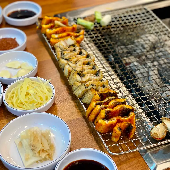 그릴 위에서 구워지고 있는 고기 조각들과 곁들임 찬들