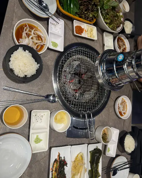 테이블 위에 놓인 숯불, 밥, 소스, 쌈 채소 등 다양한 식재료
