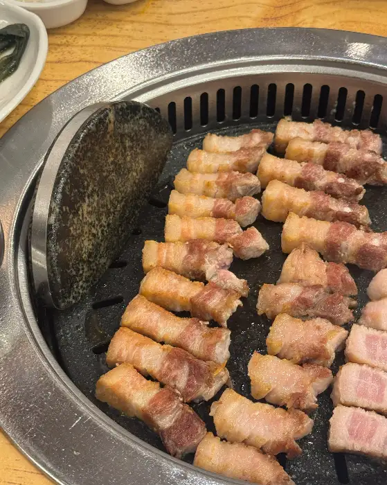 잘 구워진 삼겹살이 불판 위에 가지런히 놓여 있다.