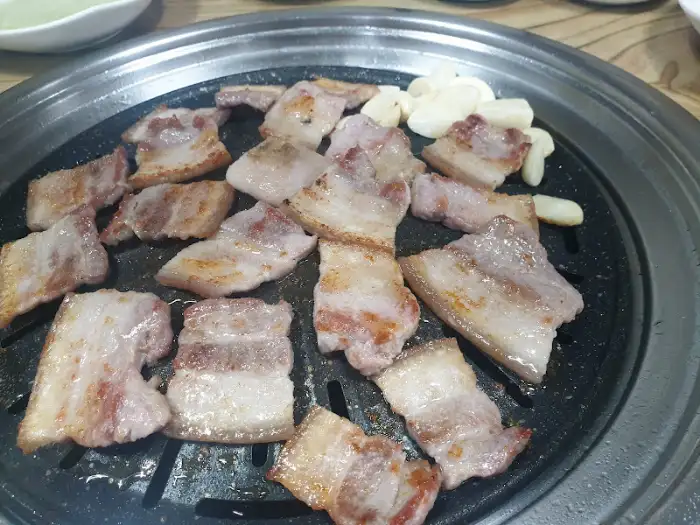 신선한 삼겹살과 마늘이 함께 구워지고 있는 모습