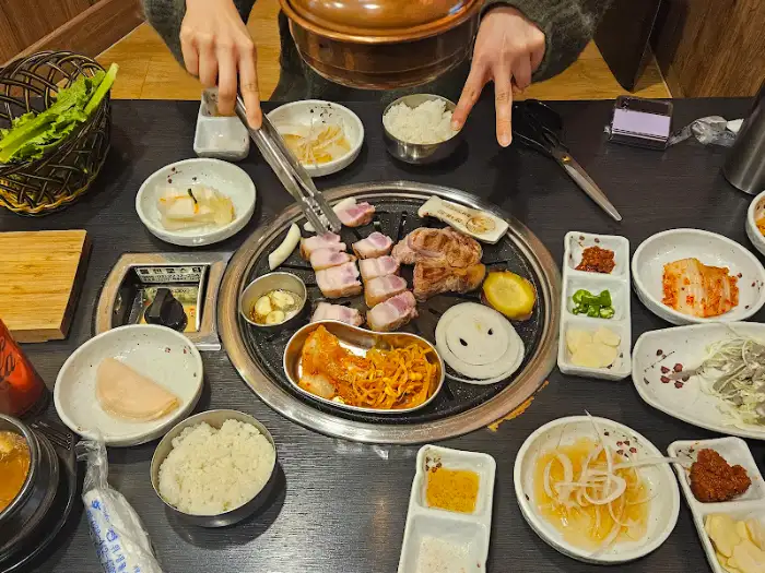 고기를 굽는 사람의 손과 숯불 위 고기