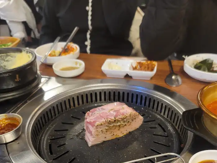 불판 위에서 구워지는 두툼한 고기 덩어리