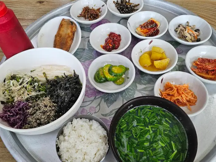 재첩회덮밥과 다양한 반찬 구성