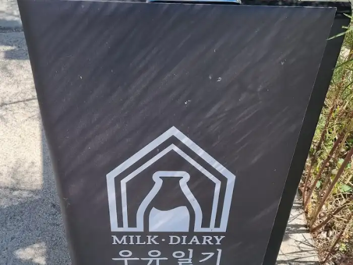 'MILK DIARY' 로고가 새겨진 검정색 안내 표지판